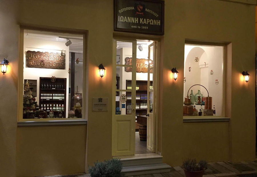 front view by night of illuminated Karonis Distillery store with two glasswindows